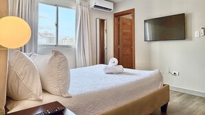 Habitación de hotel con cama, cortinas, equipo de aire acondicionado, televisor y control remoto.