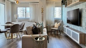 Una sala de estar moderna con sofá, sillas, una mesa de centro, televisor y comedor.