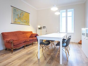 A room with a white table, four chairs, a red patterned sofa, a map on the wall, and a window. - Beautiful apartment for 6 people with WIFI, balcony and panoramic view (Cocconato)