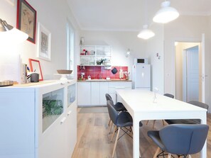 Eine moderne Küche mit weißen Schränken, einem Esstisch mit Stühlen und einem Kühlschrank.