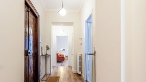 Ein Flur mit Holzboden, einem Heizkörper, einer Tür und einem Stuhl im Hintergrund.