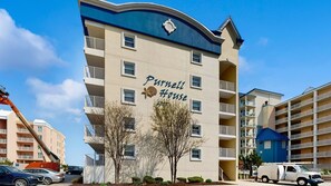 A multi-story building with balconies, a sign reading 'Purnell House,' and a crane in the foreground. - Purnell House 206 (Ocean City)