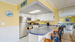 A kitchen with white cabinets, a granite countertop, and a refrigerator. - Purnell House 206 (Ocean City)