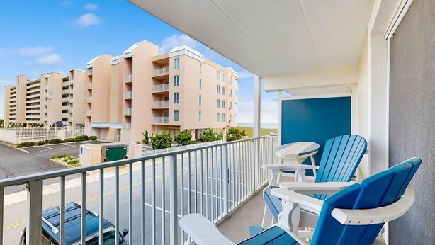 A balcony with chairs, a view of buildings, and a clear sky. - Purnell House 206 (Ocean City)