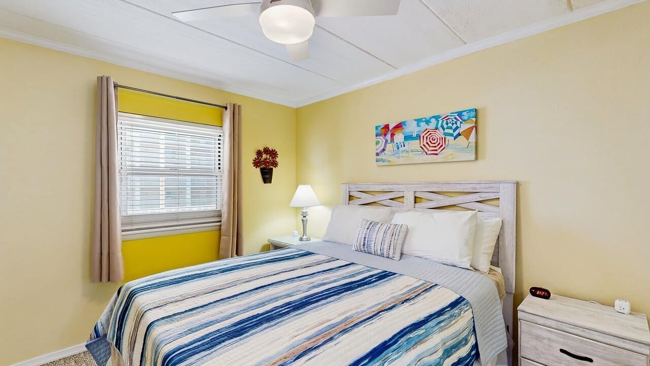 Une chambre à coucher avec un lit, une table de chevet, une lampe, une horloge murale et un tableau.