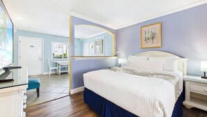 Quarto de hotel com uma cama, mesa de cabeceira e escrivaninha com cadeira.