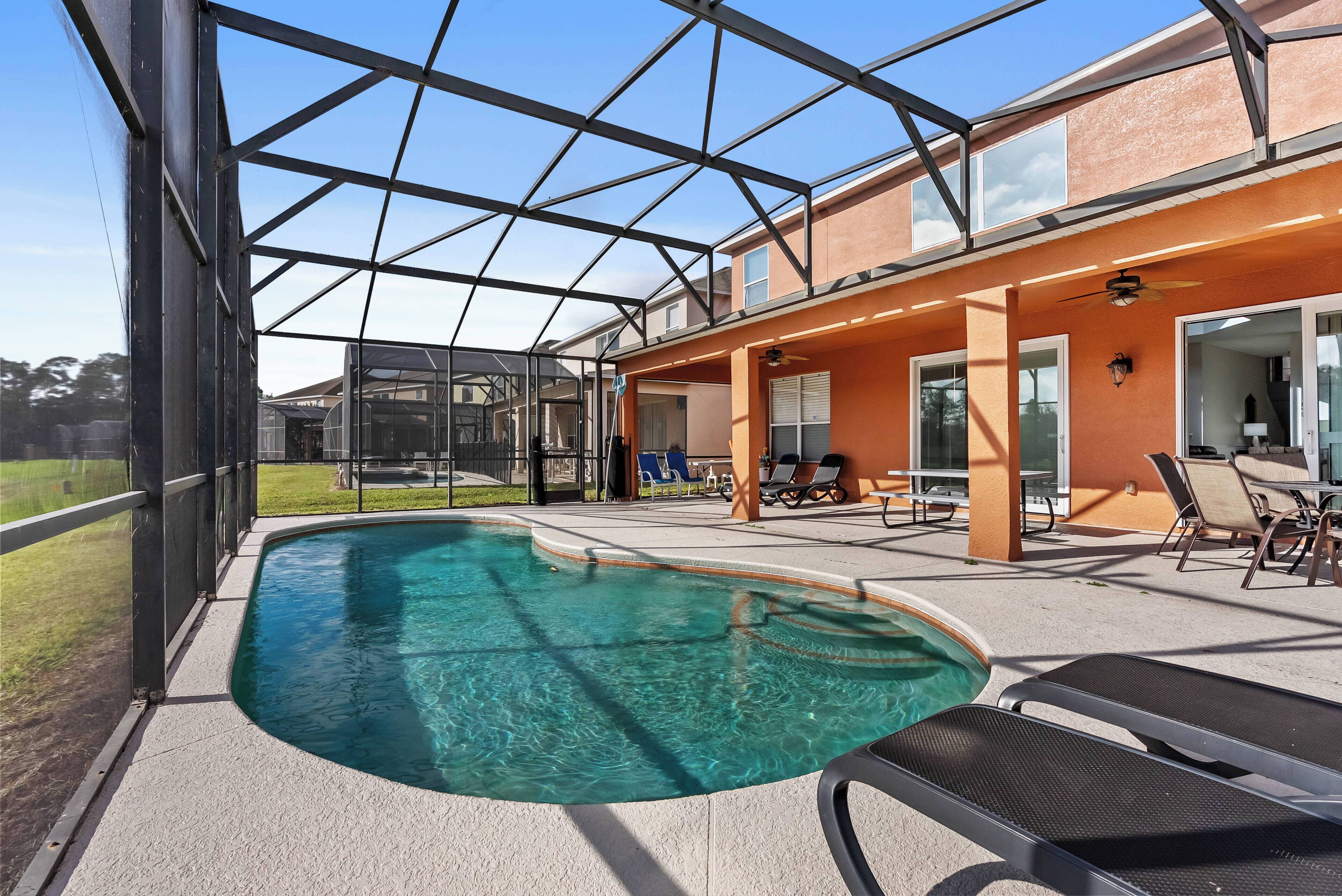 Relax in your private pool area with sparkling waters and a spacious screen enclosure. The warm orange tones of the home add a cozy vibe, complemented by comfortable lounge chairs ideal for soaking up the sun.