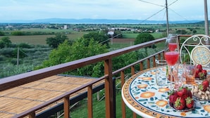 Een balkon met een tafel gedekt voor twee, met uitzicht op een landelijk gebied.