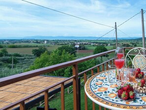 Un balcon avec une table dressée pour deux personnes, donnant sur un paysage rural.