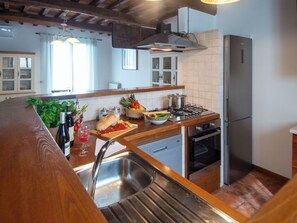 Eine Küche mit Holzarbeitsplatte, Edelstahlspüle und einem eingebauten Backofen.