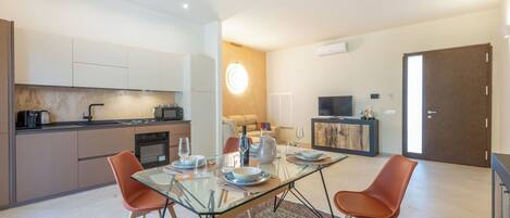 A modern kitchen with a dining area, a TV, and a door.
