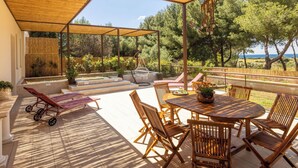 Eine Terrasse im Freien mit Holztisch und -stühlen, einer Schaukel und einem überdachten Sitzbereich.
