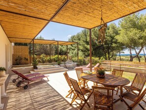 Eine Terrasse im Freien mit Holztisch und -stühlen, einer Schaukel und einem überdachten Sitzbereich.