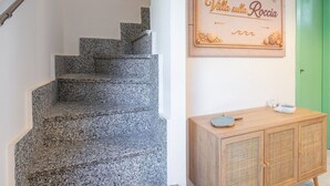 Een trap met granieten treden, een houten kast met een gevlochten paneel en een wandbord met een nautisch thema.