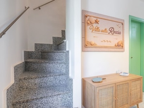 Eine Treppe mit Granitstufen, ein Holzschrank mit einem gewobenen Vorderpaneel und ein Wandzeichen im Seestil.