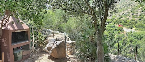 A natural outdoor setting with a small structure, possibly a shelter, and a stone wall.