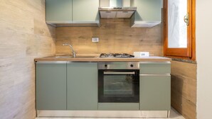 Een kleine keuken met een gasfornuis, oven en spoelbak.