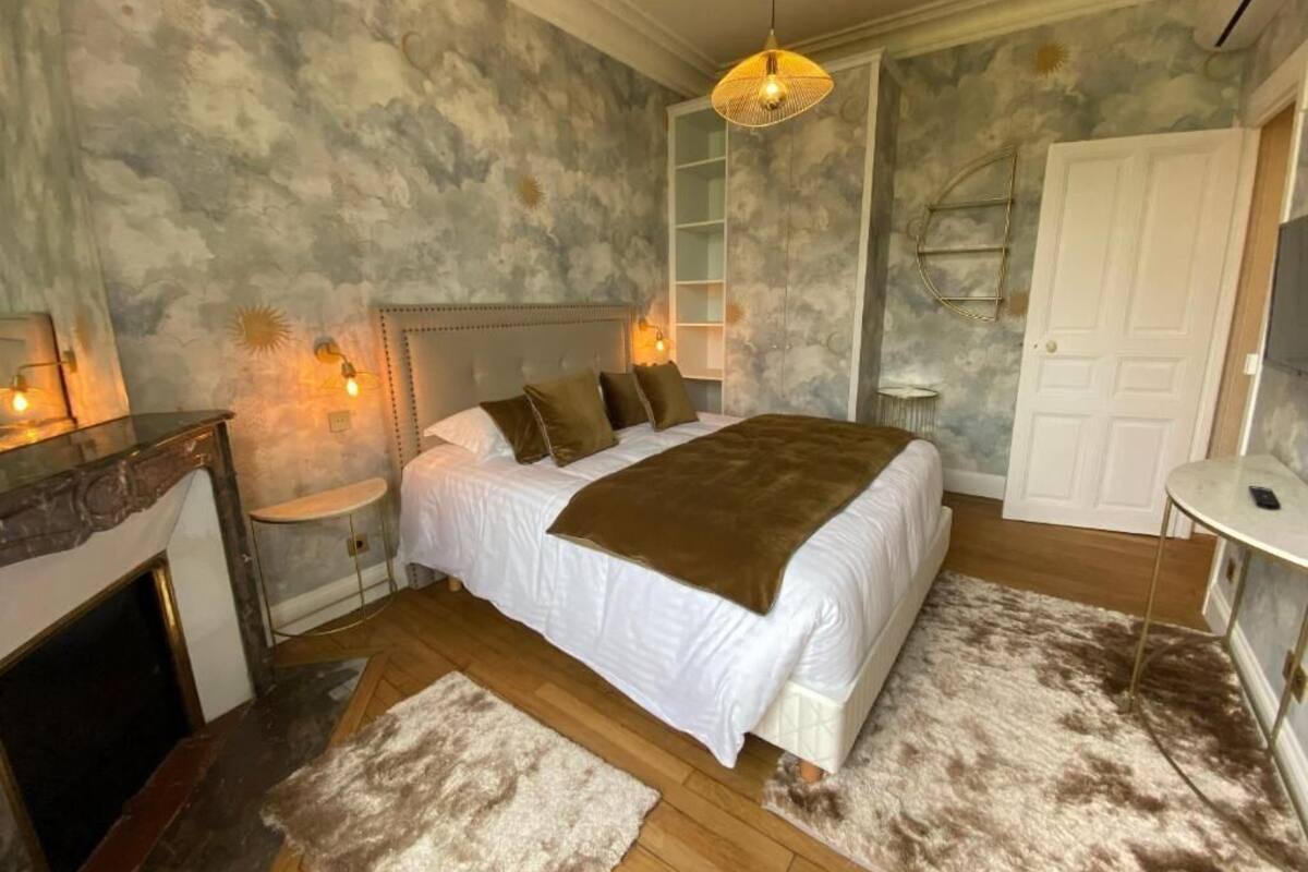 A bedroom with a bed, bedside tables, a fireplace, and a wardrobe.