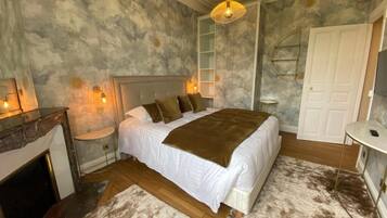 A bedroom with a bed, bedside tables, a fireplace, and a wardrobe.