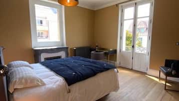 A bedroom with a bed, a desk, a chair, a radiator, and a window.