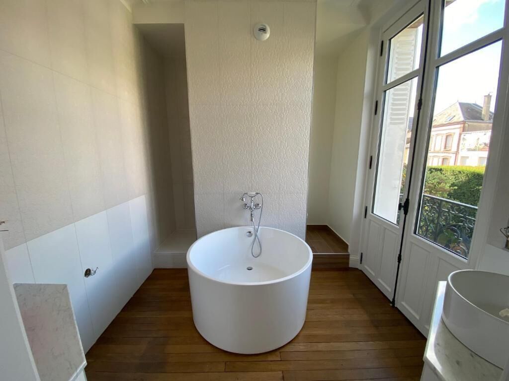 Une salle de bain avec une baignoire sur pieds, une fenêtre et une porte.