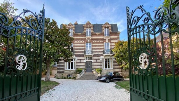 A gated entrance to a building with a driveway leading to a parked car. - Villa Gabriel Maison Blanche Chartres (Chartres)