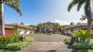 Un complejo residencial con varias casas de dos pisos, un camino pavimentado y jardines ajardinados con plantas tropicales.