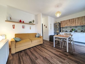 A modern kitchen with wooden cabinets, a dining table, and a sofa in a living area. - Nice apartment for 2 people with A/C, WIFI, private pool, TV and terrace (Termini Imerese)