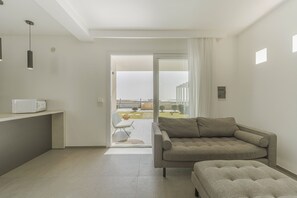 Ein modernes Wohnzimmer mit Sofa, Hocker und einem kleinen Tisch mit eingebauter Mikrowelle.