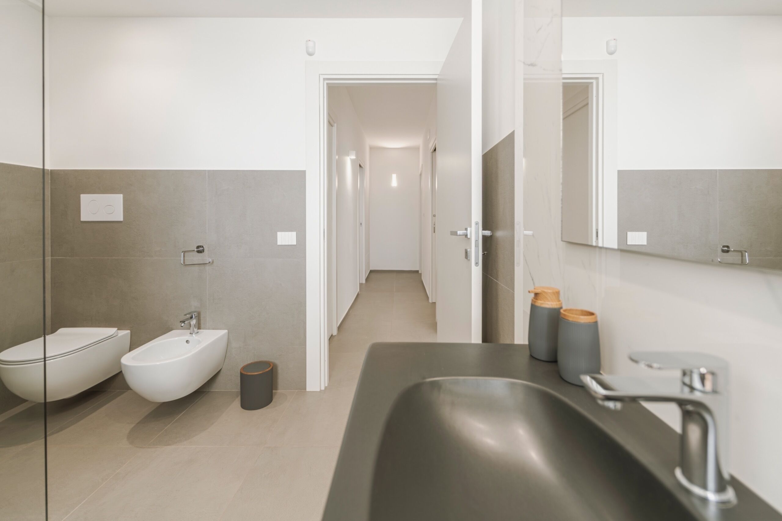 Ein modernes Badezimmer mit einer Bidet, einem Waschbecken und einem Spiegel.