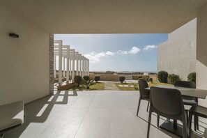 Eine moderne Außenpatio mit Blick, ausgestattet mit einem Tisch, Stühlen, einer Pergola und einem gepflegten Garten.