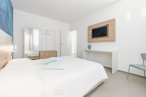 Ein modernes Schlafzimmer mit einem großen Bett, einer Holzkommode, einem Schreibtisch und einem Sessel.