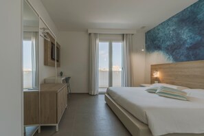 Ein Hotelzimmer mit Bett, Holz-Kopfteil, großem Fenster mit Vorhängen, einem Wand-Fernseher und einem Gemälde.
