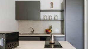 Una cucina moderna con mobili grigi, un lavello in acciaio inossidabile e un forno a microonde.