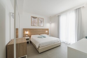 Ein modernes Hotelzimmer mit einem hölzernen Kopfteil, einem Bett mit weißer Bettwäsche, einem Nachttisch und einem Schreibtisch.