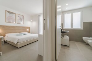 Et moderne soveværelse med seng, natbord og badeværelse med håndvask og toilet.