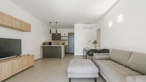 Un soggiorno moderno con una televisione a schermo piatto, un divano grigio e un poggiapiedi.