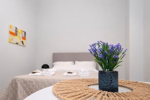 A neatly arranged bedroom with a bed, a bedside table with a vase of flowers, and a wall-mounted artwork. - Modern Seaside Escape Steps From Gytheio Harbor (East Mani)