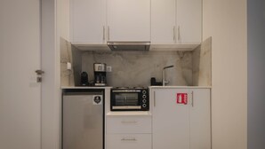 Een kleine keuken met een inbouwoven, een koffiezetapparaat en een koelkast.