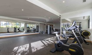 Ein Fitnessstudio mit Cardiogeräten, Krafttrainingsgeräten und großen Fenstern.