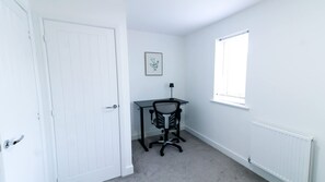 A room with a white door, a desk with a chair, a window, and a radiator. - Modern Home In Stockton-on-tees Parking Wifi (Stockton-on-Tees)