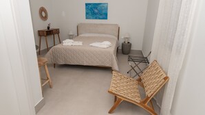 A bedroom with a bed, bedside tables, a chair, a small table with a lamp, and a painting on the wall. - Gytheio Charming Studio - Steps Away From the Sea (East Mani)
