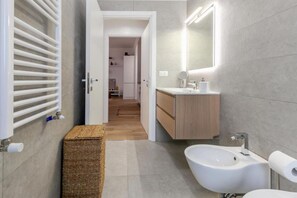 Ein modernes Badezimmer mit einer Bidet, einem Spiegel und einem Handtuchhalter.