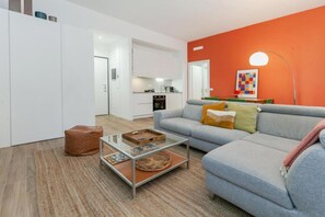 Ein modernes Wohnzimmer mit Sofa, Couchtisch und einer Küche im Hintergrund.