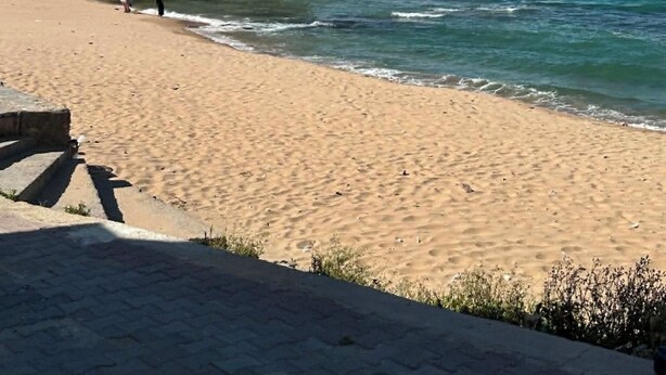 Un bâtiment situé sur la côte, doté d’un dôme, et jouxtant une plage de sable et l’océan.