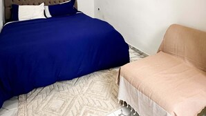 Une chambre à coucher avec un lit, une chaise et un tapis à motifs.