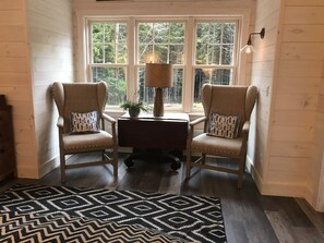 Une pièce comprenant deux fauteuils, une petite table avec une lampe et un tapis à motifs.
