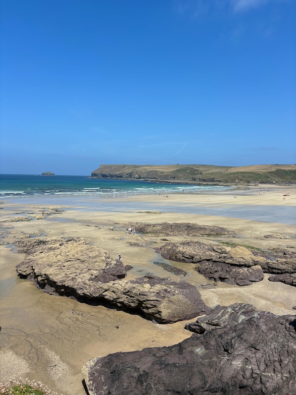 Ein Küstenstrand mit felsigem Gelände und blauem Himmel.