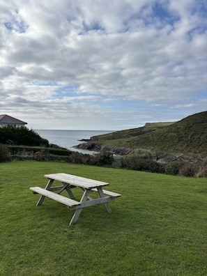 Ein Picknicktisch in einer grünen Umgebung mit Blick auf das Meer und die Hügel.