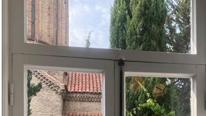 A window with a view of a brick building and greenery. - NinasPlace3 (T'bilisi)